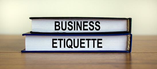 Books with text 'business etiquette' on beautiful wooden table. White background. Business concept.