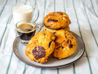 Chunky chewy chocolate chip soft cookies with cups of coffee and milk for breakfast, selective focus on cookies