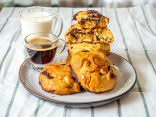 Chunky chewy chocolate chip soft cookies with cups of coffee and milk for breakfast, selective focus on cookies