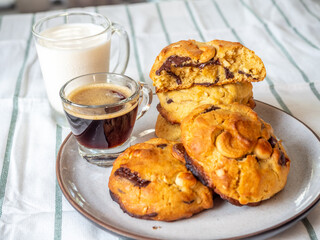 Chunky chewy chocolate chip soft cookies with cups of coffee and milk for breakfast, selective focus on cookies