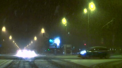 Heavy snowfall falling on the city streets at night. Drive through the town until the fall of heavy snow