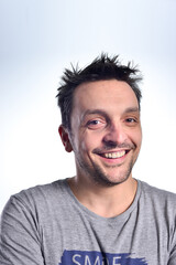 Fototapeta premium Young man dressed casual, sitting on a white chair, doing face expressions, isolated in white.