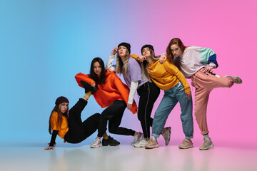 Group of dancers, boys and girls dancing hip-hop in stylish clothes on colorful gradient background...