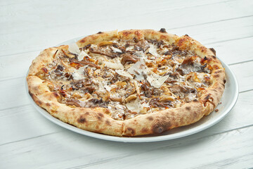 Appetizing, homemade pizza with different mushrooms, parmesan and white sauce on a white plate on a white wooden background