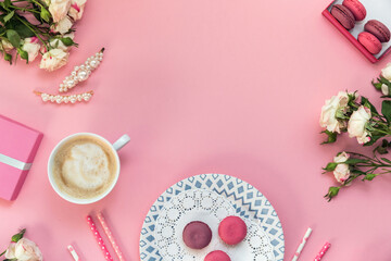 Fototapeta na wymiar Flatlay pink coral background, the cup of cappuccino coffee and sweets macaroons, spring white roses, giftbox, beauty stuff - hair pin, nail polish and parfum. Best gift for woman