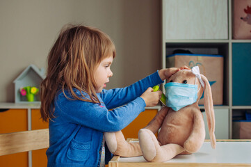 Toddler girl playing doctor giving an injection bunny toy