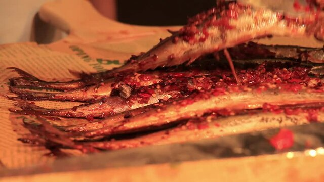 Closeup of a plate of freshly spicy fish, chef putting fish on wooden plate