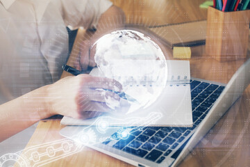 Double exposure of hands making notes with world map hologram and data theme icons. Concept of international network data.
