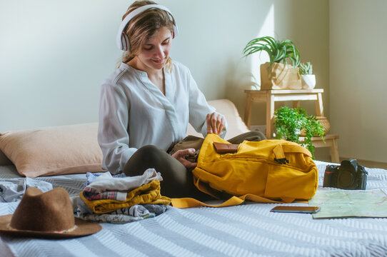 Young woman packing her backpack in the living room