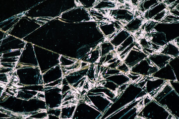 Broken glass of a phone with a crack as a cobweb close-up
