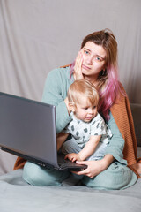 A young woman works at home with a laptop, along with a child.the son wants to communicate with his mother, they make noise and interfere with work.isolation during the coronovirus pandemic