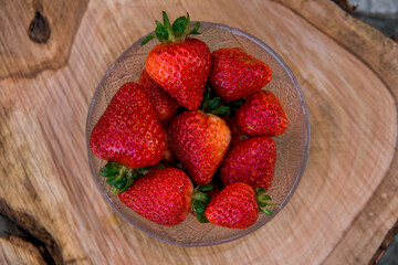 Crystal bowl full of strawberries in a wooden table. Top view.
