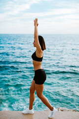 Fototapeta na wymiar sexy athletic woman stretching exercises outdoors with sea view