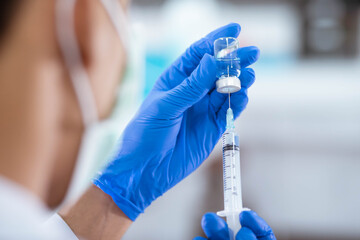 Doctor in blue glove filling syringe with vaccine