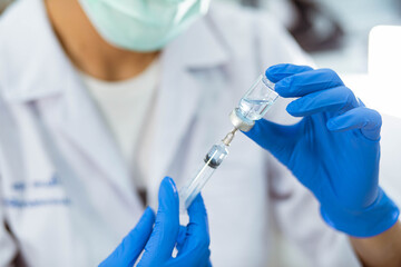 Doctor in blue glove filling syringe with vaccine