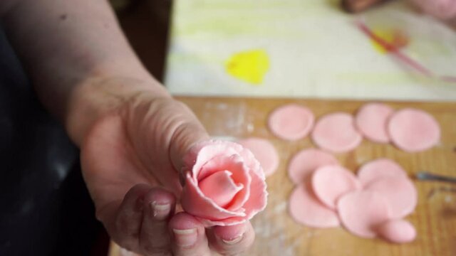 woman makes a pink roses for cake decoration, sugar mastic flowers