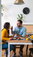 Smiling man feeding happy woman stock photo. Wife and husband eating breakfast together 