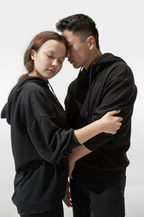 Support. Trendy fashionable couple isolated on white studio background. Stylish woman and man posing in basic minimal stylish clothes equally suitable for both. Concept of equality, inclusive.