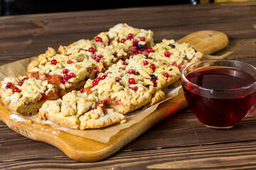 sliced ​​homemade grated pie with berries on a wooden board.