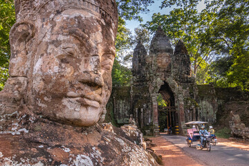 A tuk-tuk travels through an ancient stone archway leading to a temple in Angkor Wat Cambodia