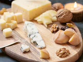 Cheese plate from different kind of cheese - Emmental, Homemade, Parmesan, blue cheese, bread sticks, walnuts, raisin, pear, grapes on a table