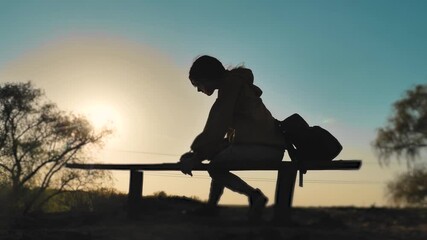 new kind of business remote online work freedom a concept. silhouette girl working in not at home. teenage girl with a digital tablet sits on a bench silhouette at lifestyle sunset