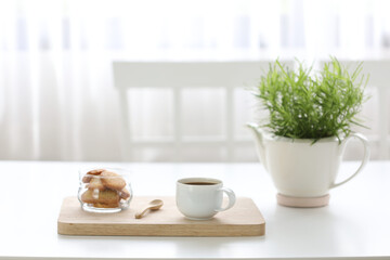 coffee with cookies on white desk with green plant pot minimal cozy home