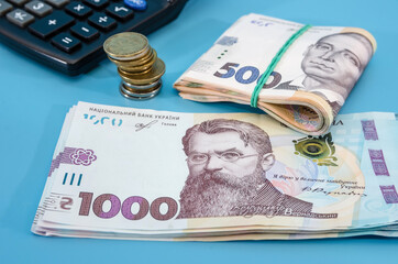 500 and 1000 hryvnia with coins and a calculator on a blue background. Much money. Financial concept. Close-up. hryvnia stacks.
