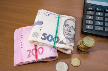 200 and 500 hryvnia with coins and a calculator on the table. savings concept. Much money.