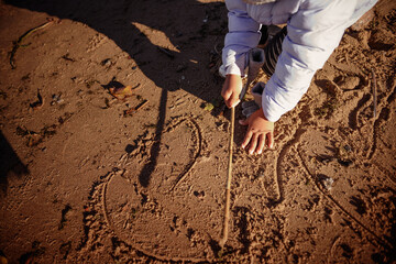 Toddler girl wearing jacket portrait and playing with the stick.