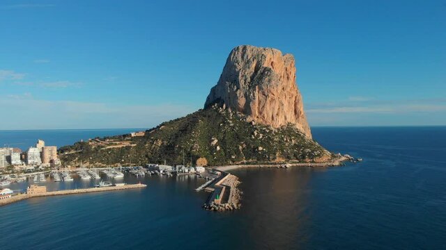 Drone point of view to Penon de Ifach or Penyal d'Ifac limestone cliff located at Natural Park of Calpe resort town. Mediterranean Sea, sunny day and harbour. Province of Alicante, Costa Blanca, Spain