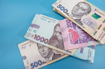 different ukrainian banknotes on a blue background. 200, 500 and 1000 hryvnias.