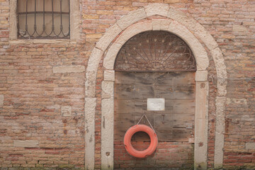 A life ring is strategically positioned on a wooden door surrounded by a brick wall 
