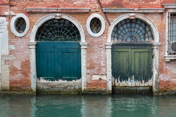 Obraz premium Rustic weathered doors in venice italy reflected in the canal