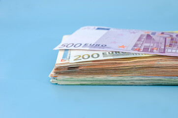 stack with different euro banknotes isolated on a blue background. Much money.