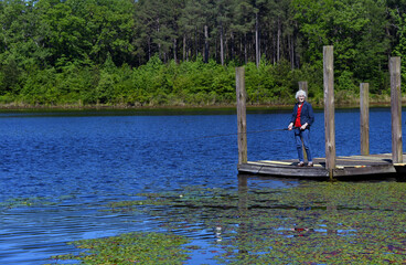 Fototapeta na wymiar Elderly Fisherwoman Enjoys a Day on the Lake