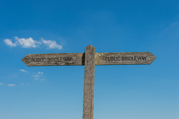 wooden public bridleway sign with blue sky