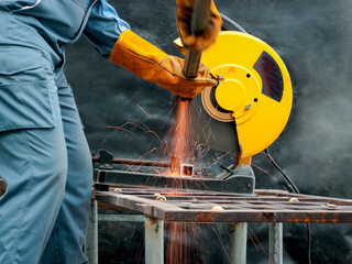 Industrial worker wearing safety mask, helmet, and safe glasses cutting steel or welding metal...
