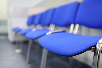 Line of empty blue visitor chairs at reception or in bank