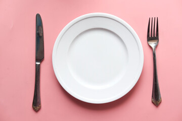 Clean plate and cutlery on pink background