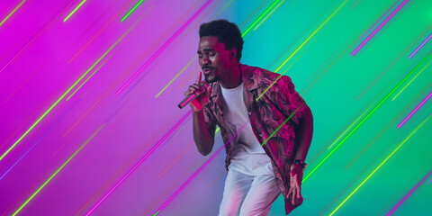 Man singing, performing. Creative portrait with copyspace. Neon lighted, colored portrait with neon lines, flyer, proposal. Motion, action, youth culture concept. Contemporary art, modern design.