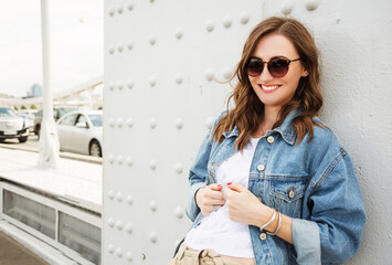 Outdoors fashion portrait of cheerful trendy woman posing on the street. Smiling and walking on the...