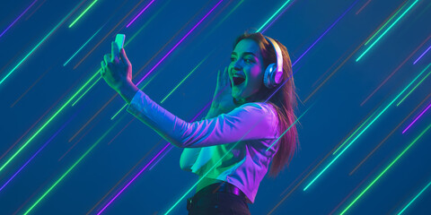 Woman listen to music in headphones. Creative portrait with copyspace. Neon lighted, colored portrait with neon, flyer, proposal. Motion, action, youth culture concept. Contemporary art, modern design