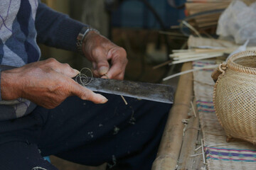 Old hand man using knife to make bamboo sharpener, to make invention