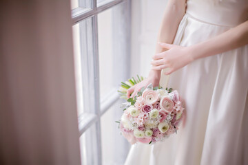 The bride holds a beautiful bouquet of roses and peonies