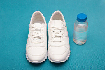  Fitness concept with white sneakers and a water bottle. Top view on a blue background. Copy space