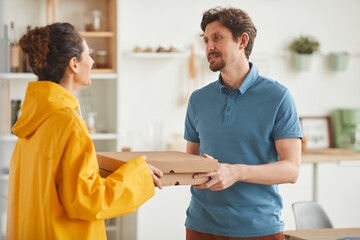 Fototapeta premium Young woman delivering pizza she standing and delivering pizza to man to home
