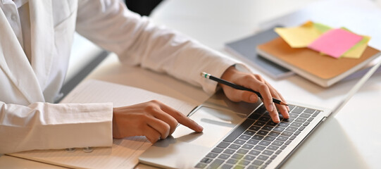 Hands of a businesswoman are taking notes while working with a computer laptop that putting on a...