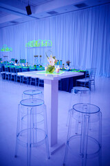 Luxury orchid cocktail flower arrangement on lucite stools and table set up for a party in a ballroom.