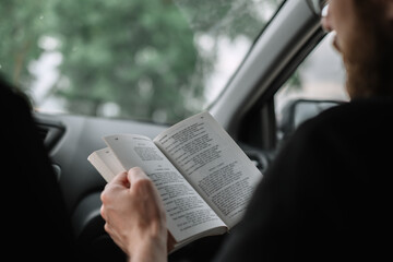 Man reading book in a car during a long trip.